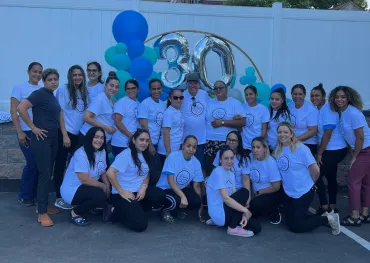 merry maids team members with balloons standing in front of a white fence